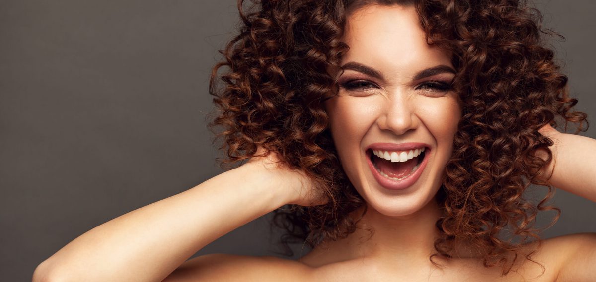 mujer de cabello rizado acomodando sus ondas